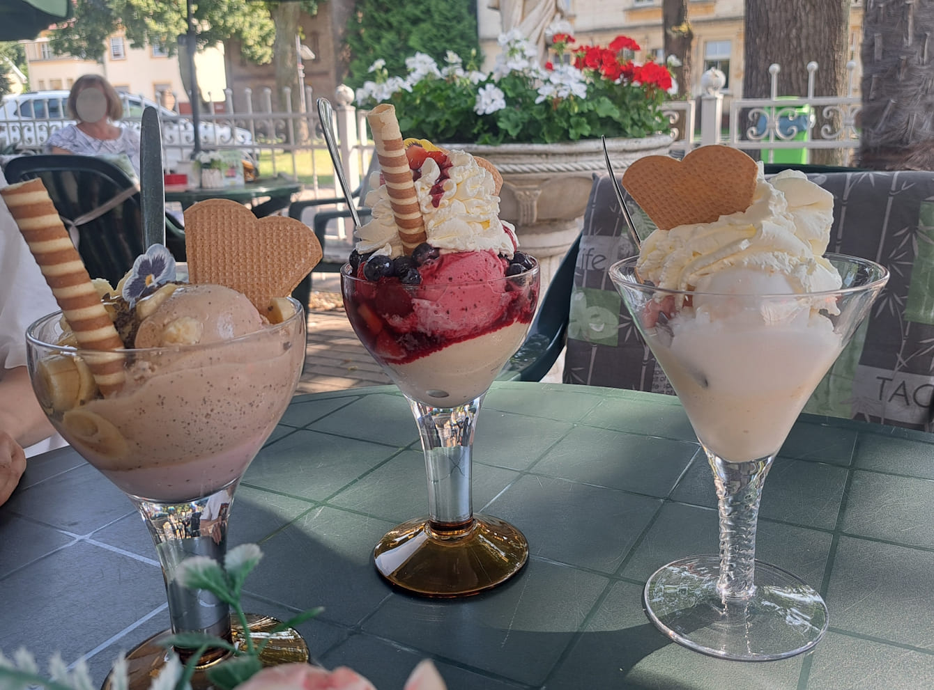 Drei große Eisbecher stehen auf einem Tisch.