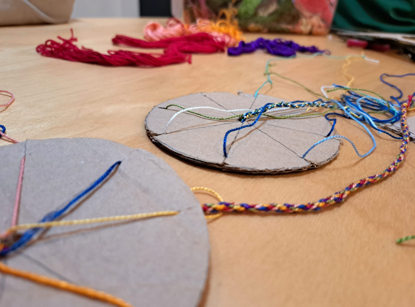 Tisch mit selbst gebastelten Kumihimo-Scheiben zum Knüpfen von Armbändern