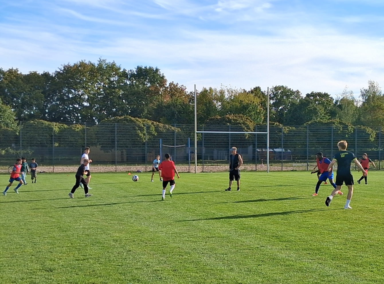 Jugendliche spielen auf einem Rasenplatz Fußball.