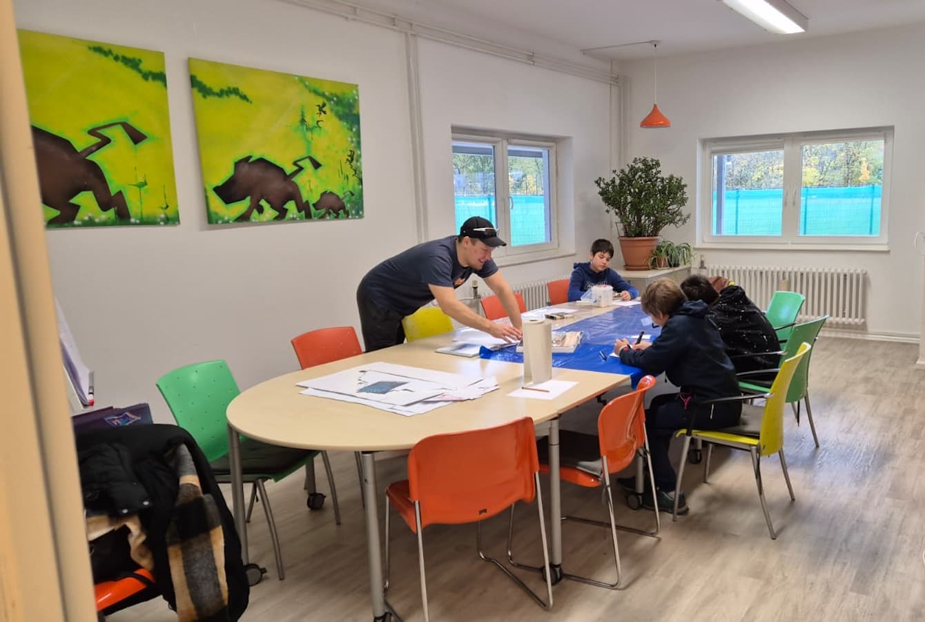 Eine Gruppe Jungs sitzt um einen Tisch und zeichnet.