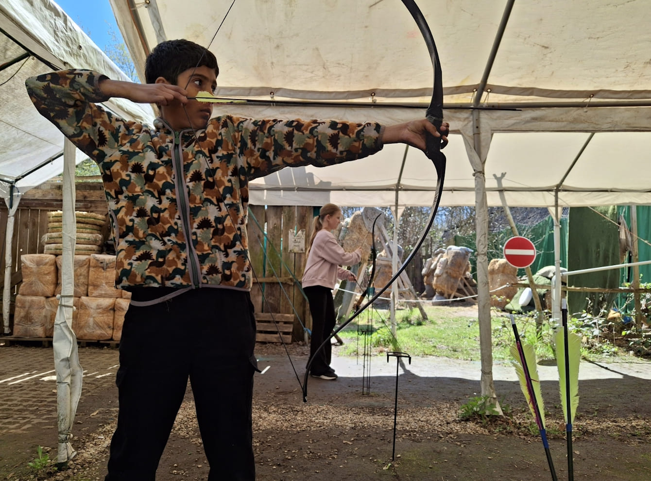 Junge schießt mit Pfeil und Bogen an einem Übungsstand.