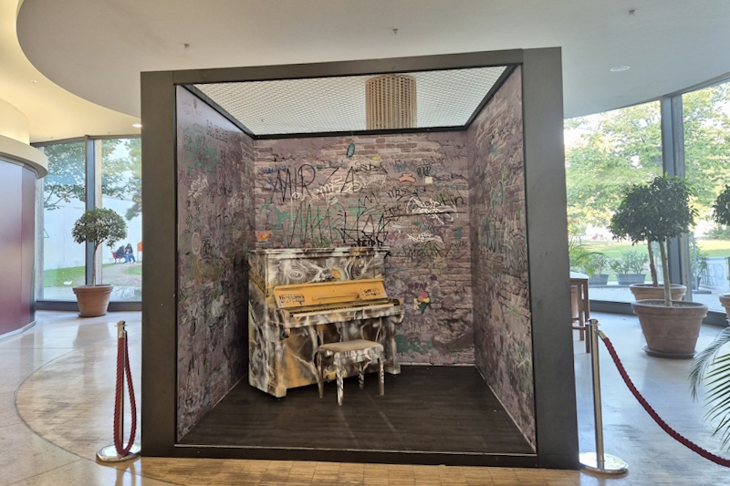 Buntes, mit Graffities bemaltes Piano in einer großen Fotobox in einem Einkaufszentrum