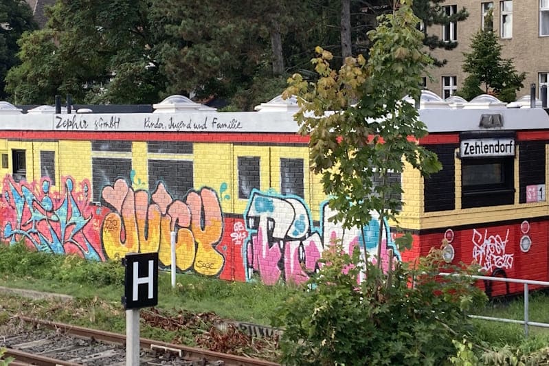 Bunter S-Bahn-Waggon mit verschiedenen Pieces, der auf eine Hauswand gesprayt wurde.