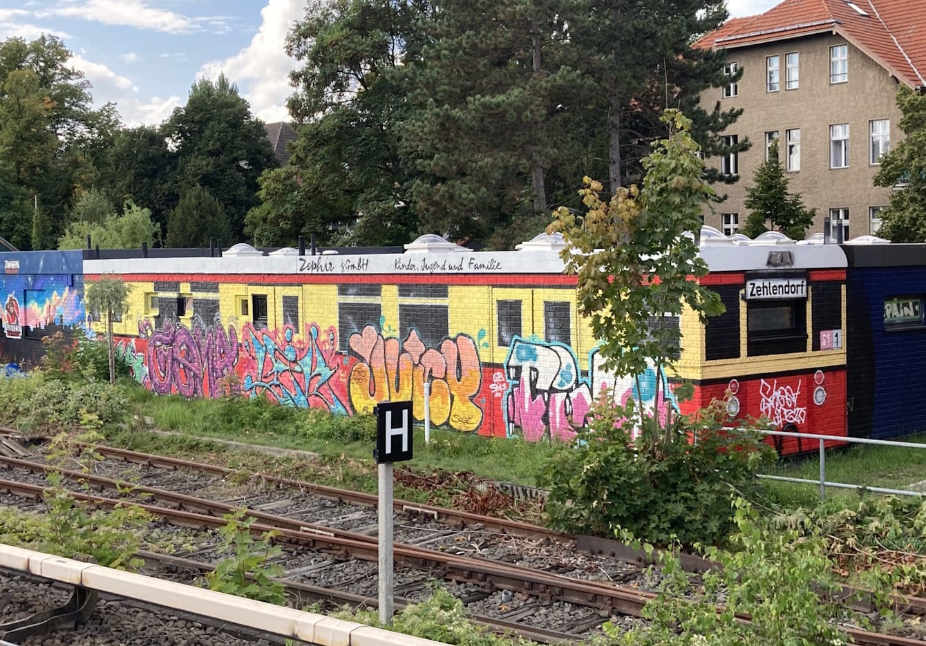 Auf der Rückseite des Hauses Anhaltiner Str. 7 gesprayter rot-gelber S-Bahn-Waggon mit bunten Pieces.