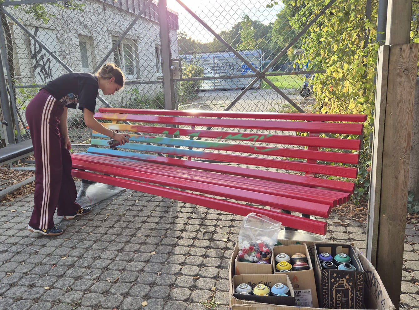 Junge Frau besprüht eine rote Bank mit Graffitis