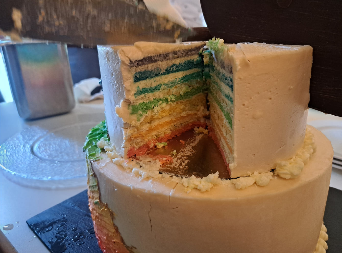 Angeschnittene, zweistöckige Torte mit Tortenböden in Regenbogenfarben